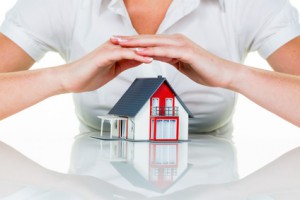 Eine Frau beschützt Ihr Haus und Eigenheim. Gute Versicherung und seriöse Finanzierung beruhigen.